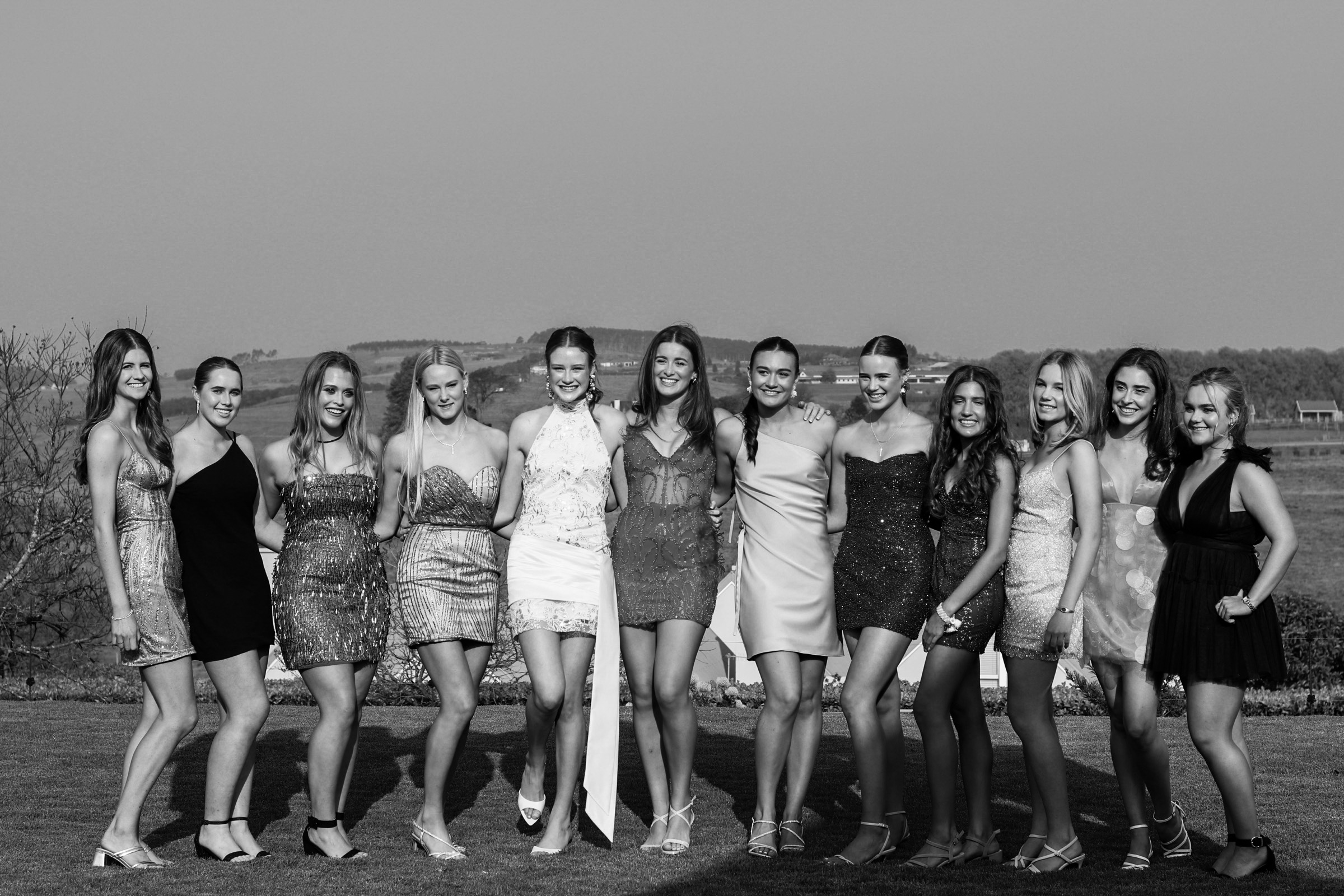 A line of matric dance guests in formal dress, black and white.